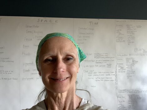 A woman with a green bandana on her head in front of a graph of
words smiles at the camera. Photo courtesy of the artist.