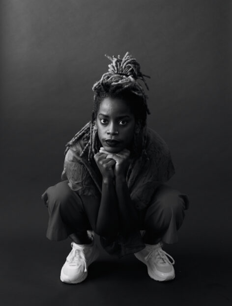 A black and white photo of Angie in a squat, Photo by Whitney Browne.