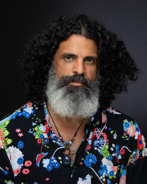 A portrait of Antonio wearing a Hawaiian shirt; he has a long beard and a sassy expression. Photo courtesy of artist.