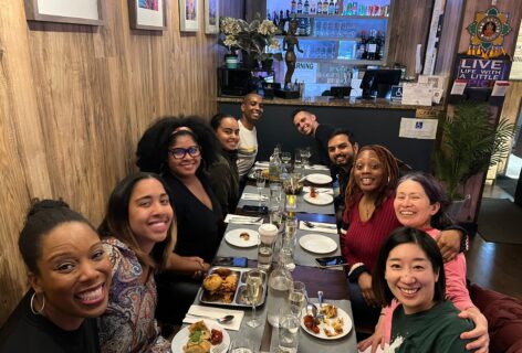 Artist of Color Council members and MR@Juson artists curated through this advisory board enjoying dinner together. The smile are all looking and smiling at the camera, food and drinks on the dinner table. Photo by Megan Curet.