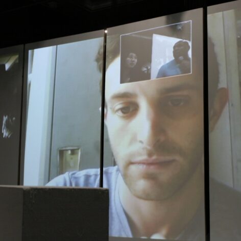 Joshua Lubin-Levy in a virtual meeting projected on a 3 panel screen. Photo courtesy of Joshua Lubin-Levy.