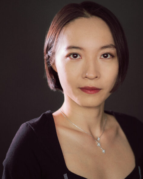 Star, an Asian woman with her black hair around jaw, wearing black shirt with a star-shaped necklace. She looks straight to the camera, with calm and a smile. Photo courtesy of the artist.