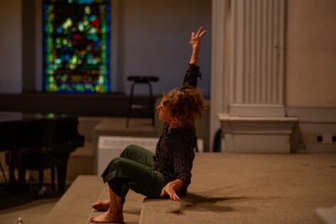 A photo of Vicky Shick during her Summer MELT workshop. She sits at the altar at the St. Marks Church bending her torso to one side and reaching her arm up. Photo by Rachel Keane