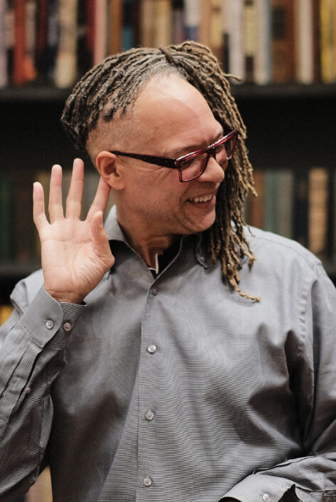 A man with dreadlocks holds a hand to his ear as he listens for information. Photo courtesy of the artist.