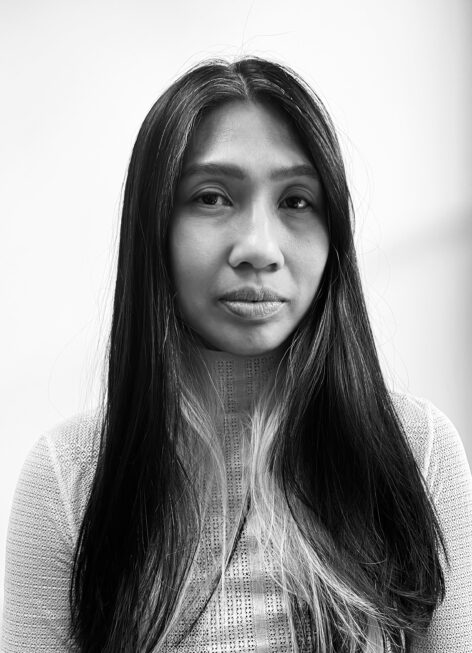 Black and white headshot of a Filipina woman with long hair wearing a textured turtleneck shirt. Photo by Seyhr Qayum