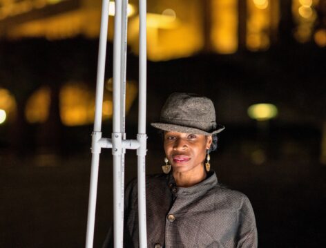 ID: Marjani standing next to frame of Memoirs of a Unicorn (horn), re-visioned with PVC Pipe for Garden of Unicorns installedat the Getty Museum. Photo by Cassia Davis. © J Paul Getty Trust 2022.
