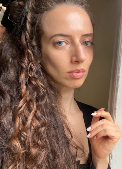 A woman with curly hair standing near window. Photo courtesy of the artist.