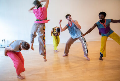 Trisha Brown Dance Company members groove, jump and lunge while wearing colorful and printed outfits. Photo by Stephanie Berger.