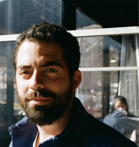 Headshot of Nicolas Noreña. He has a bears and is wearing a dark button up. He looks directly into the camera. Photo courtesy of the artist.