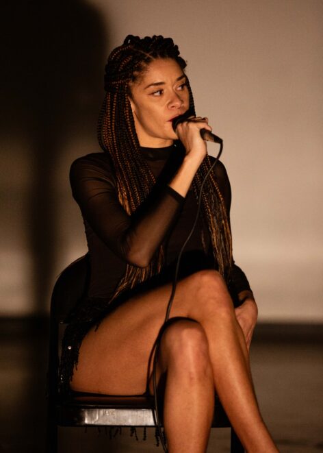 Alexandra Barbier recites a monologue into a microphone during a work-in-progress showing of her solo, 