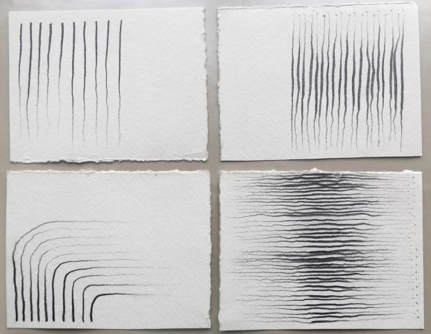 Four white rectangles of paper with raw edges sit on a grey surface. Each paper hosts a group of squiggling black ink lines arranged in various but uniform spatial and directional configurations. Image courtesy of the artist. 
