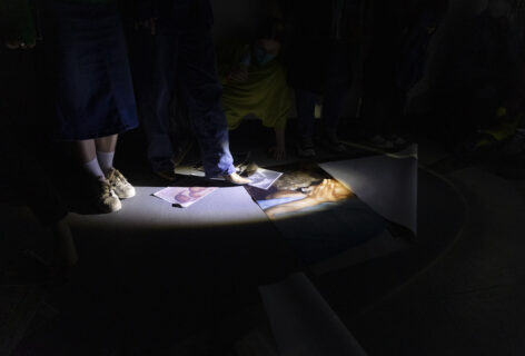 Photo of books and images being arranged on the ground in a dark lighting. Photo by Ricky Yanas.