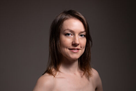 Photo of a woman's face with shoulder length hair and a soft smile. Photo courtesy of the artist.