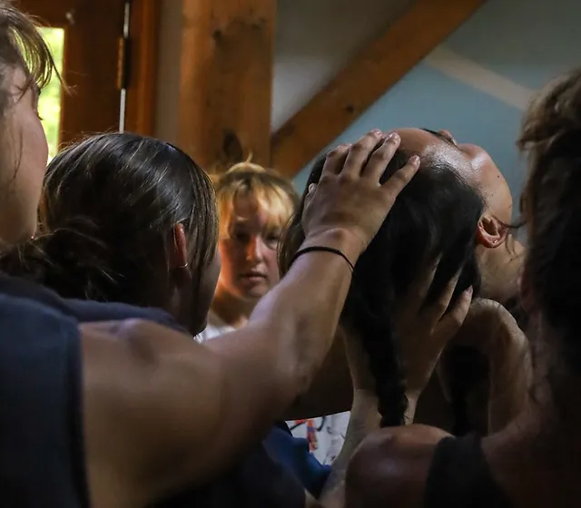 A dancer's head and neck are supported tenderly by a swath of other dancers. Photo credit to Rosa Wolff.