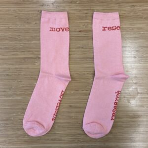 Pink socks with red text that says "Movement" and "Research" around the respective ankles and soles of each sock.