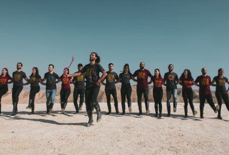Dabke performance by El-Funoun Dance Troupe in the hills of Jericho, Palestine. Line up of Dabke dancers with the Laweeh/ leader in front, dressed in jeans and El-Funoun T-Shirt and Dabke boots. Photo courtesy of the artists.