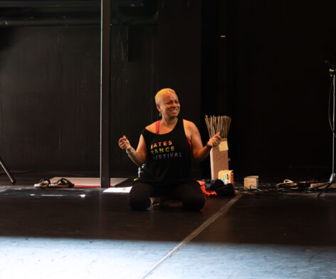 Kimani sitting on marley floor in a dance studio. Photo by Nell Mancini Photography.