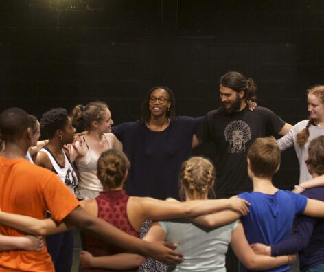 a group of dancers hold each other in a tight circle smiling and sweaty. Photo courtesy the artist.