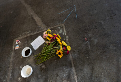 A photo of items. A bouquet, 2 white bowls, and a piece of paper with writing. Photo courtesy of artist.