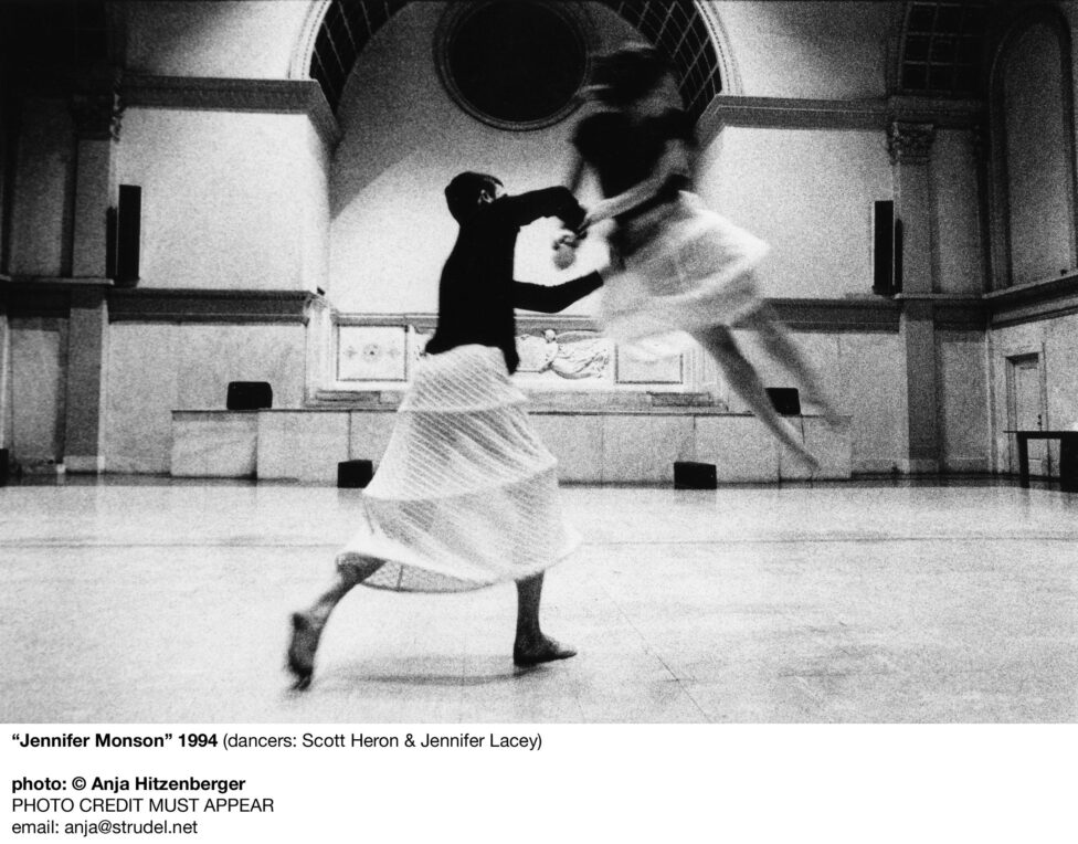 Photo of Scott Heron and Jennifer Lacey performing in the Judson Memorial Church. Scott supports Jennifer’s hip with one arm while holding on to her wrists with the other. She is in mid air in motion. They both wear skirts with structured boning. Photo by Anja Hitzenberger