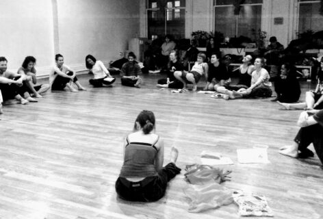 A black and white photo of a group of students sitting on the wood floor of a studio. Photo courtesy of Luce Mahler.