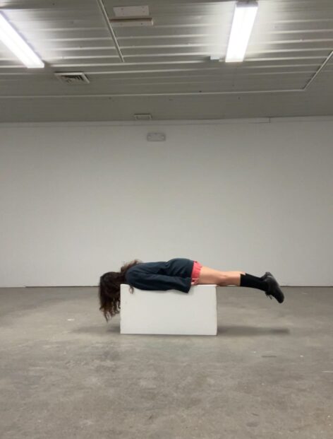 A woman lies face down on a pedestal. Photo courtesy of the artist.