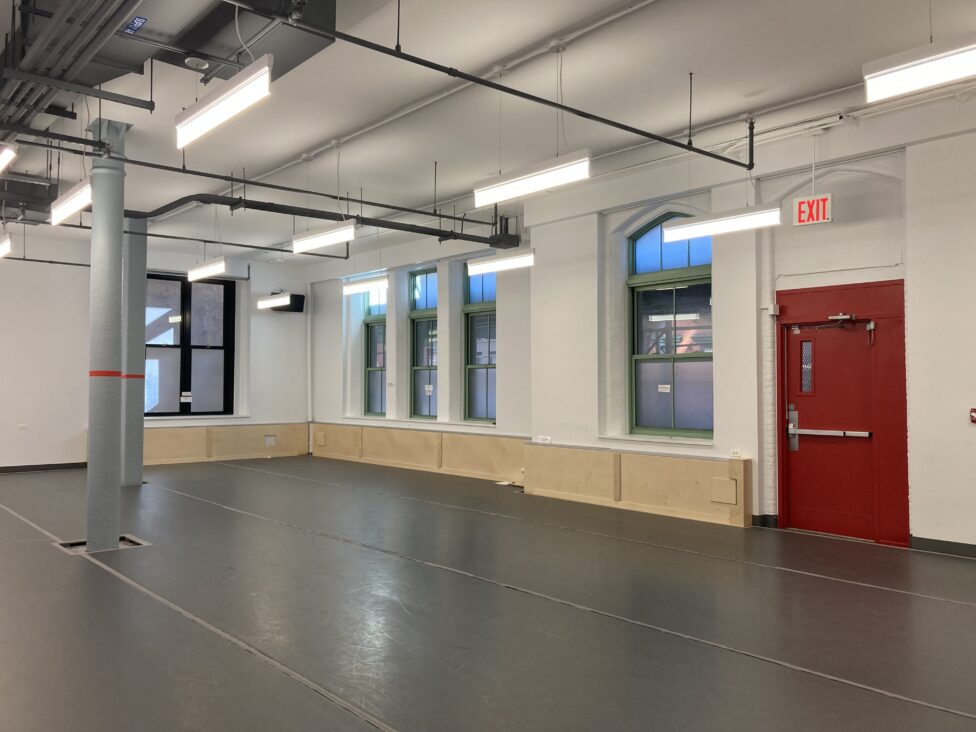 A photo of the new studio at 122CC. An empty studio with grey marly and bright fluorescent lights. Photo by Raychel Ceciro.