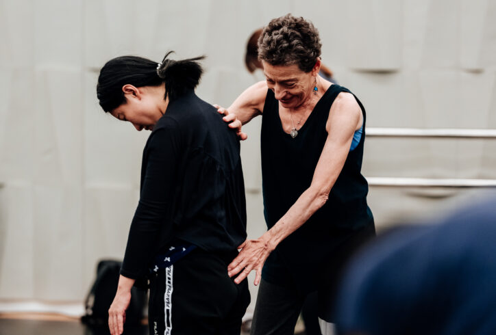 Teaching photo of Barbara Mahler from the National Kaohsiung Center for the Arts. Barbara helping a student during class; she gently places her hand on the small of the student's back and lower spine, the student brings their chin to chest.