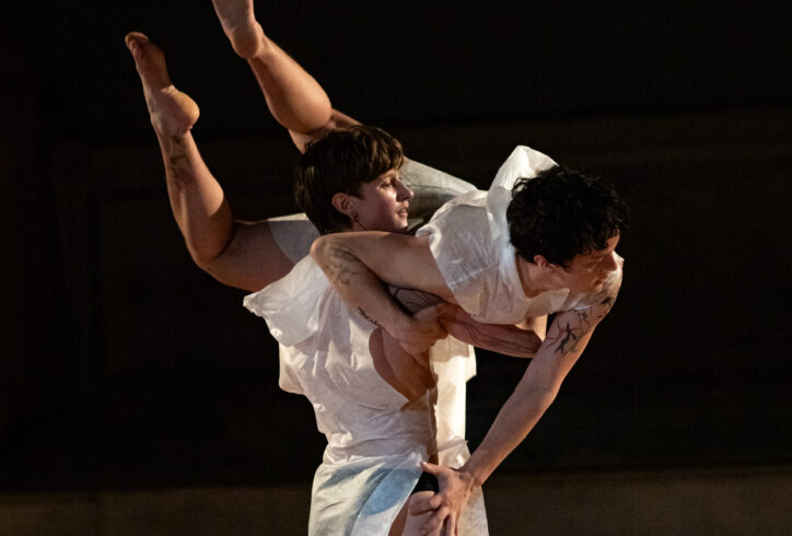 felix bryan and cove barton performing for Movement Research at the Judson Church. One dancer stands carrying the other in their arms. The other dancer arches with their feet reaching upwards. Photo by Rachel Keane.