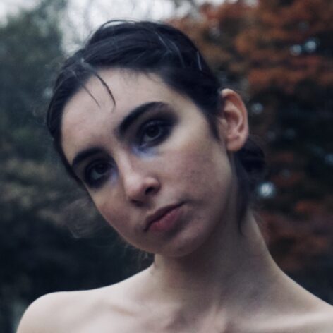 a female with dark hair, head tilted to the right
