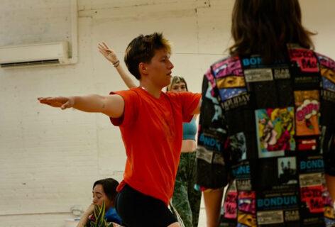 Julianna F May's class; a dancer with their arms out in T shape and one's back toward the lens, and another crouched behind. Photo by Amelia Golden