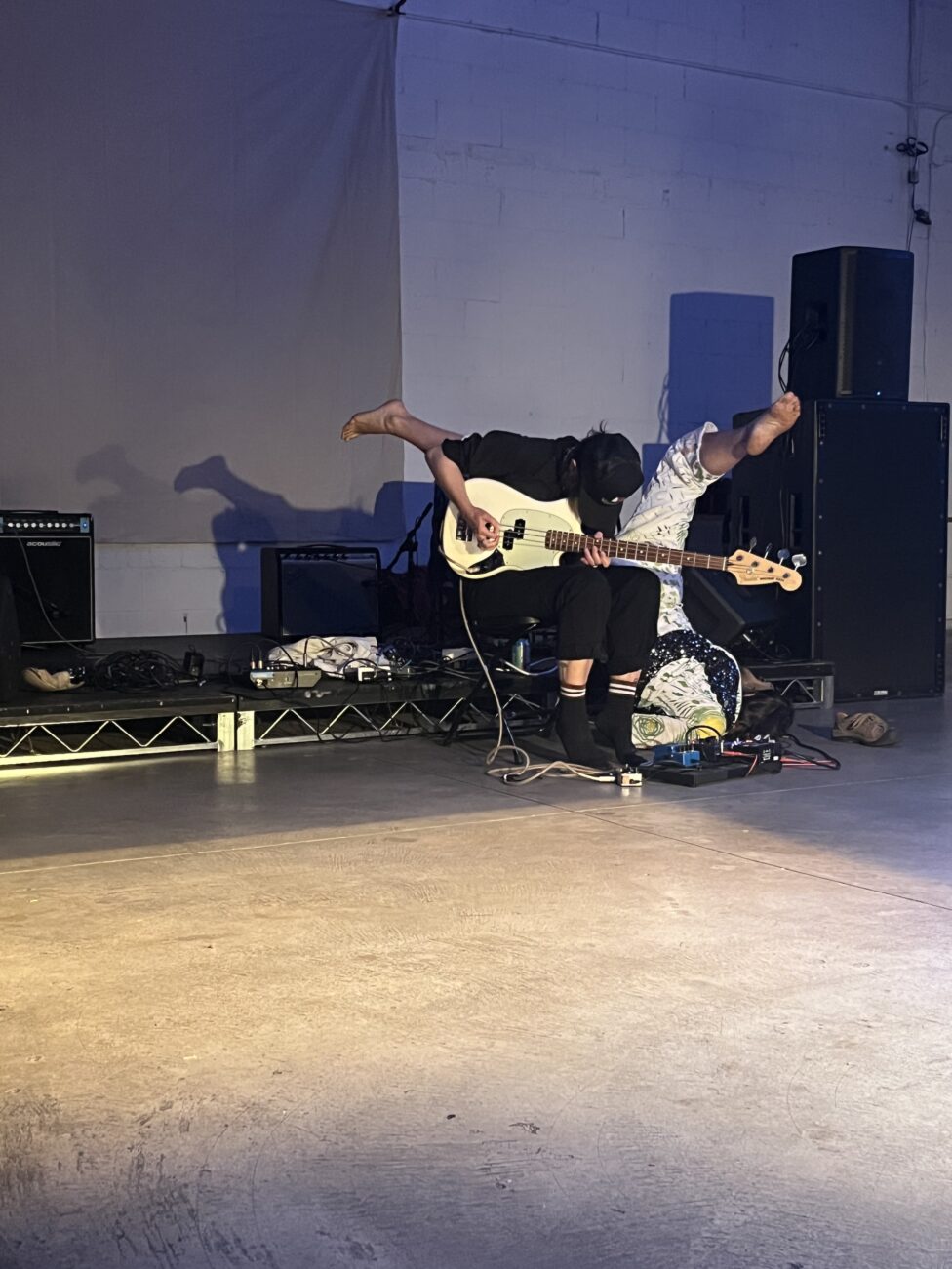 A dancer moving over someone playing the bass. March 2024. Body + Bass improvisation with Tara Jane O'Neil. 2220 Arts and Archives, Los Angeles, CA.