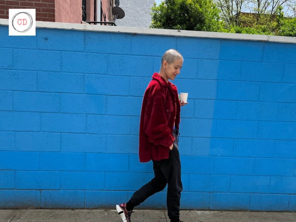 Roya walking in front of a blue wall. Days filled with long walks and friends during treatment, Bedstuy NYC