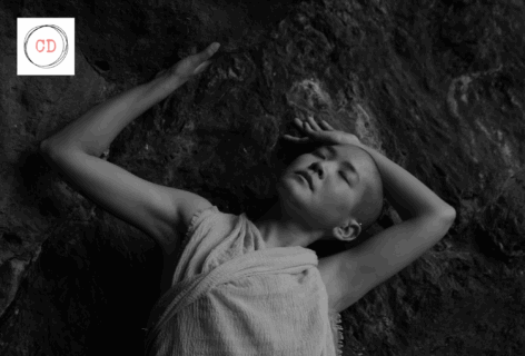 Black and white image of kyoko laying on the ground with their arms above their head. Photo by Andre Shizen.