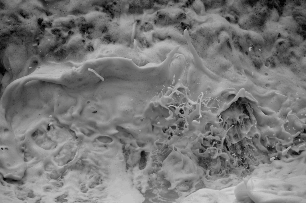 A black and white photo of sea foam. The image is textured and visceral. Photo by Andre Shizen.