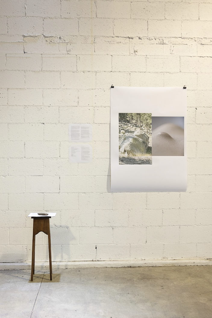 A wooden stool sits left of a white piece of paper with images on it, both presented against a white, brick wall. Photos by Argel Rojo from Kyoko’s LACE Exhibition: I’m here and I love you at 2220Arts+Archives.