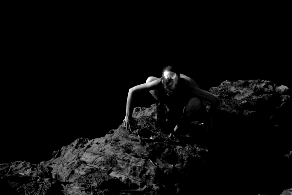 kyoko against an inky black background, crawling atop a bed of rocks. Stills of the monster from the film, courtesy of the artist.