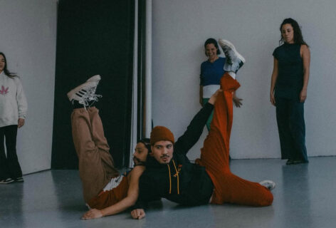 A group of 5 dancers in various positions; 2 in the center on the floor with their legs up. Photo by Camila Falquez.