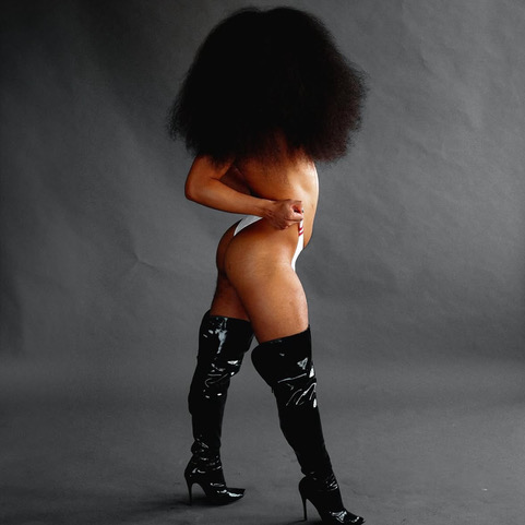 Prince stands in black heels and white bikini bottoms, their curly hair covering their face. Photo by Dior Rodriguez.