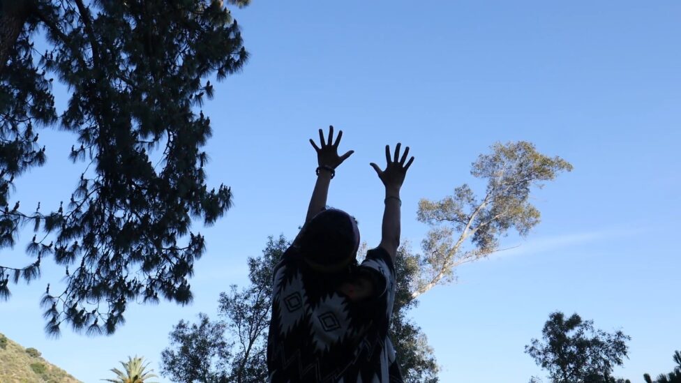 A silhouette of someone reaching towards the sky. Altadena, Tongva/Chumash land.