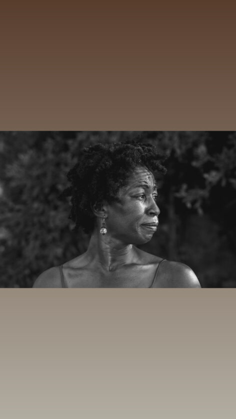 A Black woman overcome with emotion faces Southeast, looking out toward the Mediterranean Sea. Photo by Laura Bianchi, Bogliasco Center.