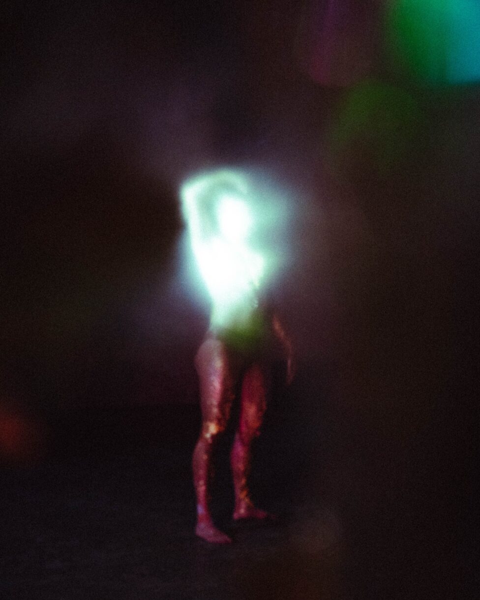 ID: Riven is a distant and blurry figure. Gold residue trails down his legs, and his torso reflects and diffuses into a flare of light.
Photo credit: Parawis Jiamchaotpattanakul