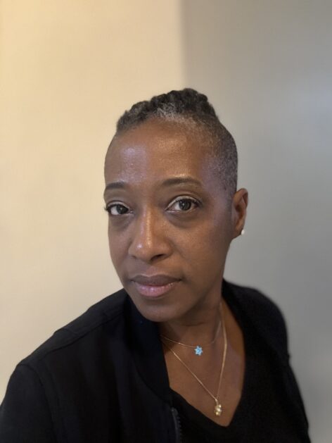 A headshot in 3/4 profile of artist with a low Mohawk, wearing a black shirt. Photo by Aaron Hyman.